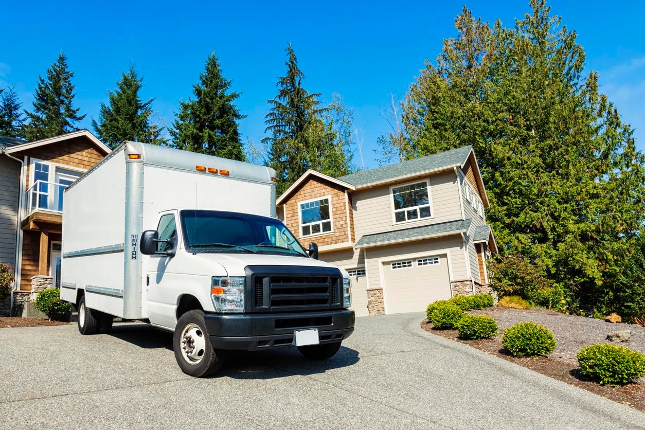A moving truck parked on the driveway of a suburban home